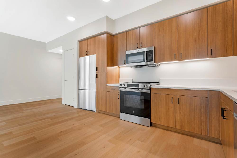 Kitchen and Dining/Living Room at The Millton with wood style plank flooring and stainless steel appliances.