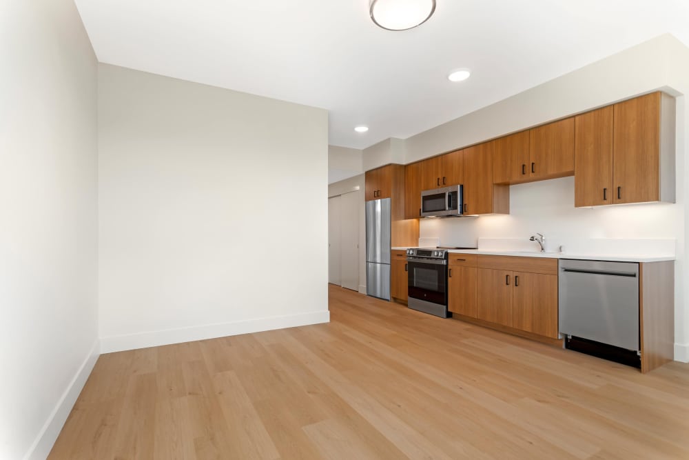 Designer granite backsplash, an island with a large quartz countertop, and floor-to-ceiling windows in a model home's kitchen at The Millton in Redwood City, California