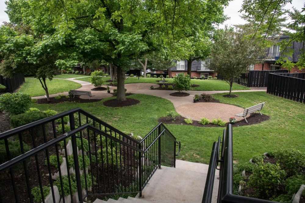 Courtyard garden with winding path, benches, and trees at Beau Jardin Apartments in St. Louis, Missouri 