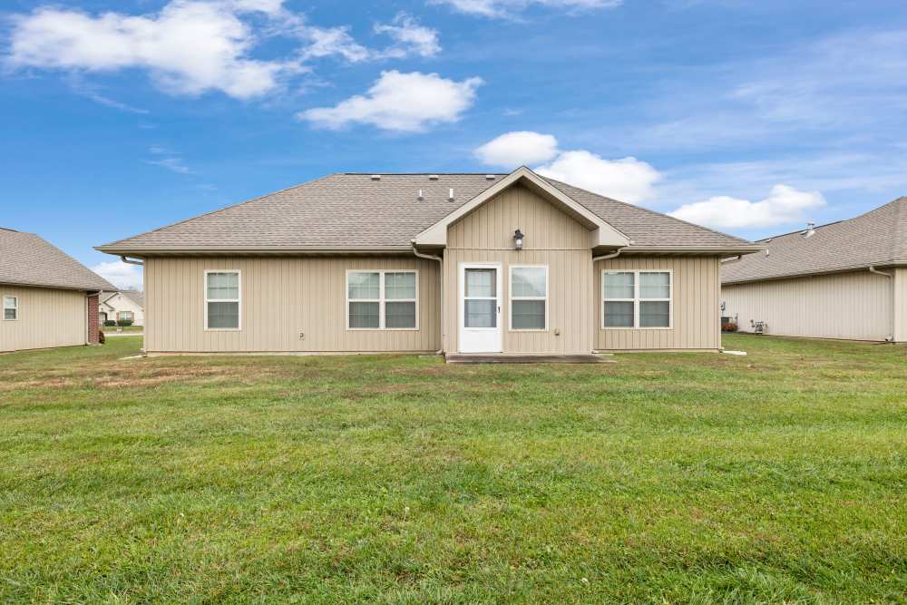 Back view of an apartment with central glass door, and double windows at Oaklawn Estates in Rogersville, Missouri