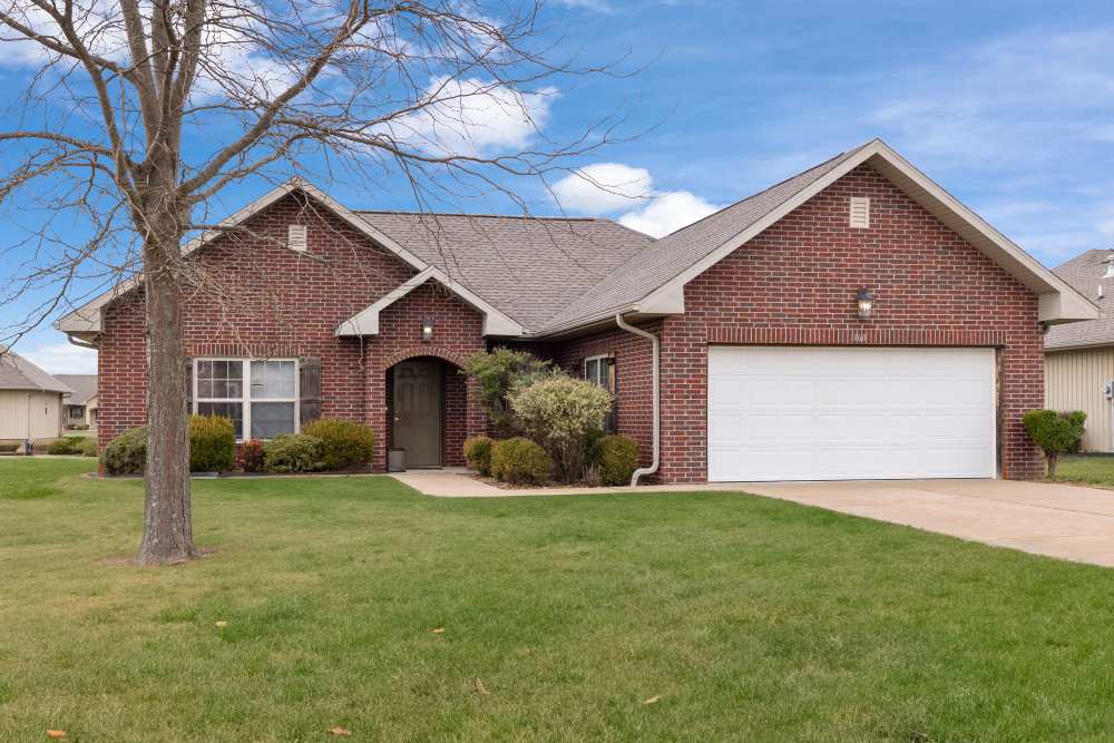 Exterior view of apartment with garage facility with green landscape at Oaklawn Estates in Rogersville, Missouri