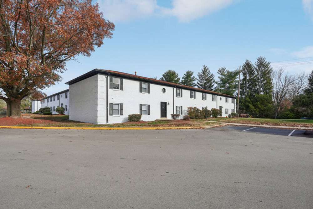 Exterior side view apartment with parking lot and autumn tree at Charleston Square Apartments in Columbus, Indiana