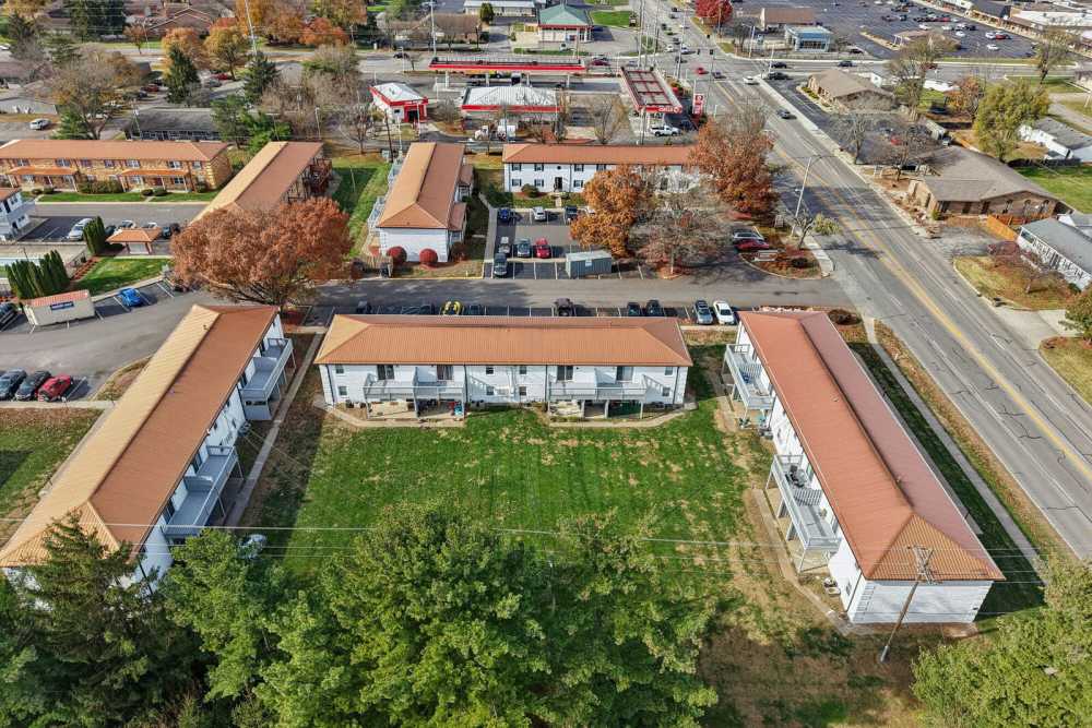 Aerial view of apartment complex with red roofs, central courtyard, parking lots, and surrounding streets at Charleston Square Apartments in Columbus, Indiana