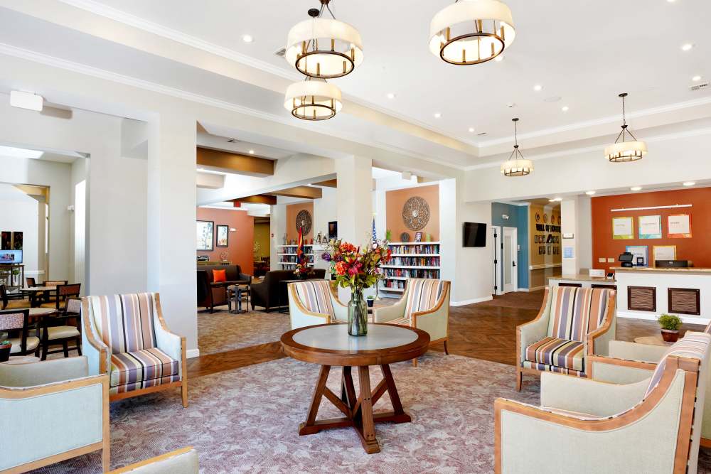 Spacious lounge with seating, bookshelves, and large windows, at Sky Vista in Mesa, Arizona