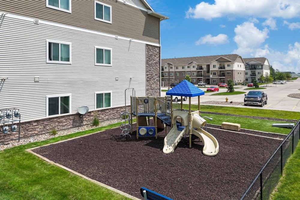 Playground with slides and grassy area near modern apartments at Alice Patricia Apartments in Waukee, Iowa