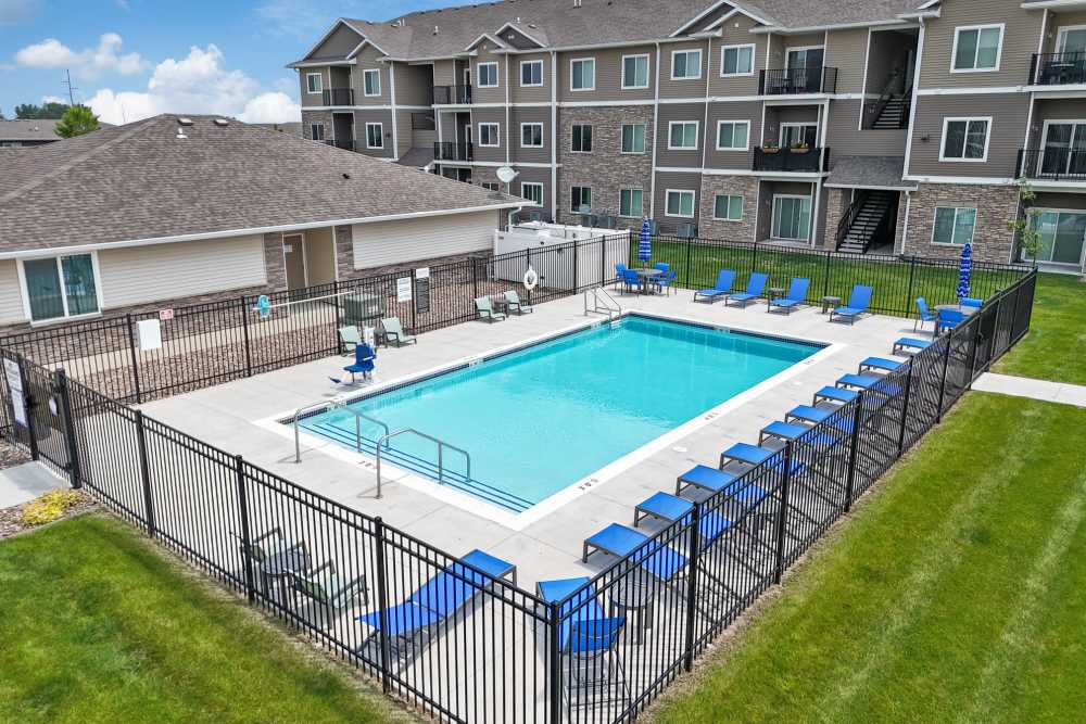 Sparkling pool surrounded by lounge chairs and lush green landscaping at Alice Patricia Apartments in Waukee, Iowa