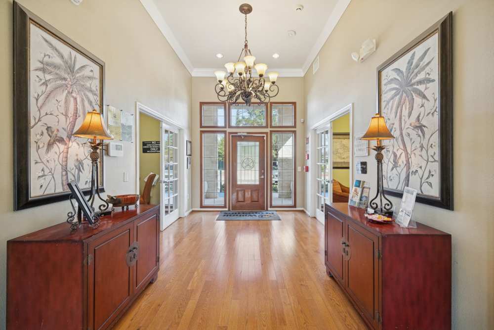 Elegant lobby with chandelier, wooden flooring, symmetrical décor, and glass-paneled entrance doors at Palm Garden in Orange, Texas