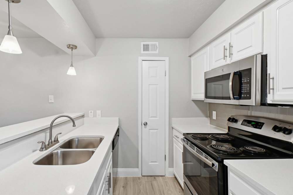 Galley-style kitchen with black appliances at Avondale Parc at Bellmar in Dallas, Texas