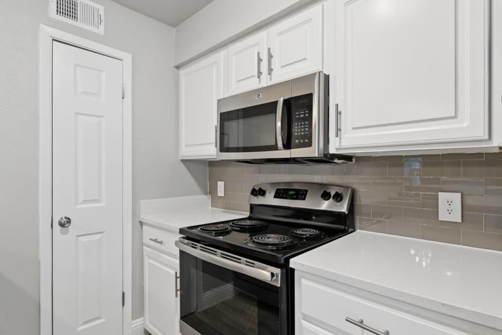 Kitchen with white cabinets and black appliances at Avondale Parc at Bellmar in Dallas, Texas