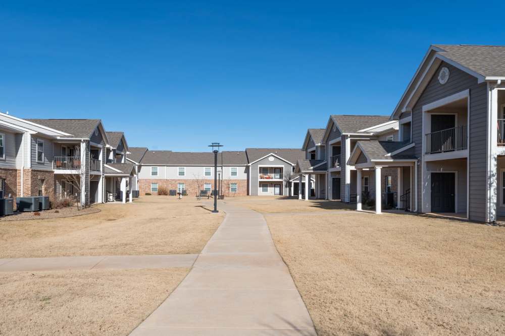 Charming apartment with well-maintained pathways and sunny sky at Savannah Terrace in Mustang, Oklahoma