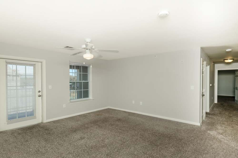 Apartment living room with carpet flooring and ceiling fan at Sunnydale Pointe in Wichita, Kansas