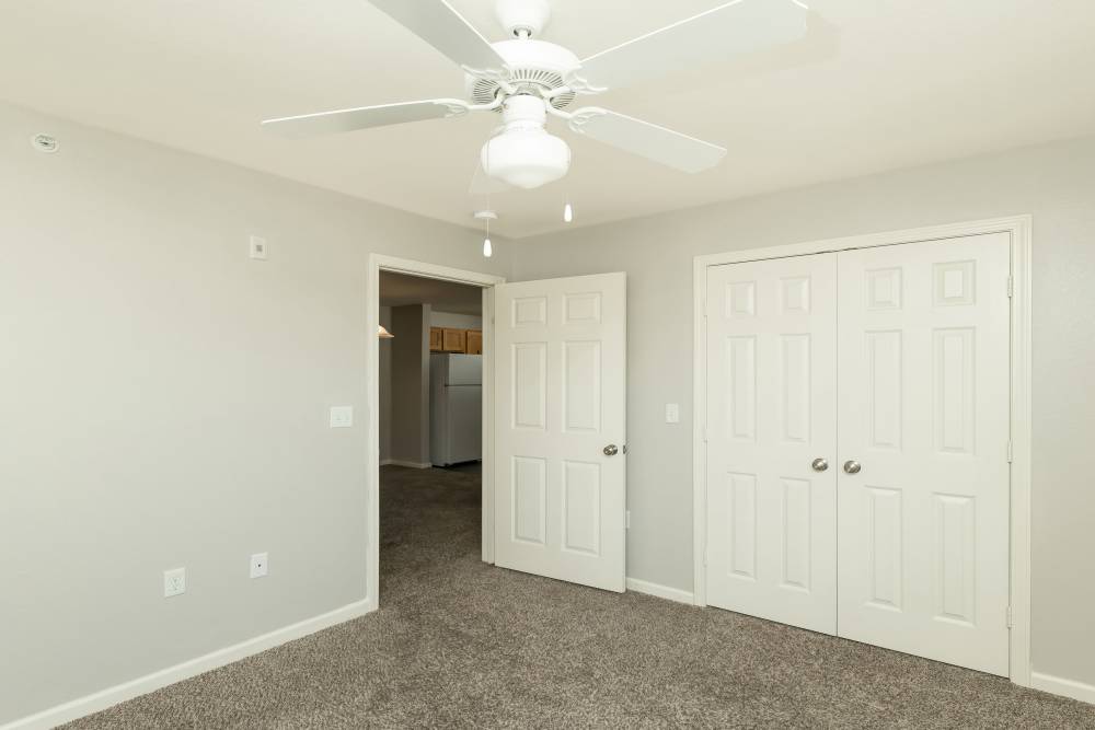Spacious bedroom with ceiling fan and carpet flooring at Sunnydale Pointe in Wichita, Kansas