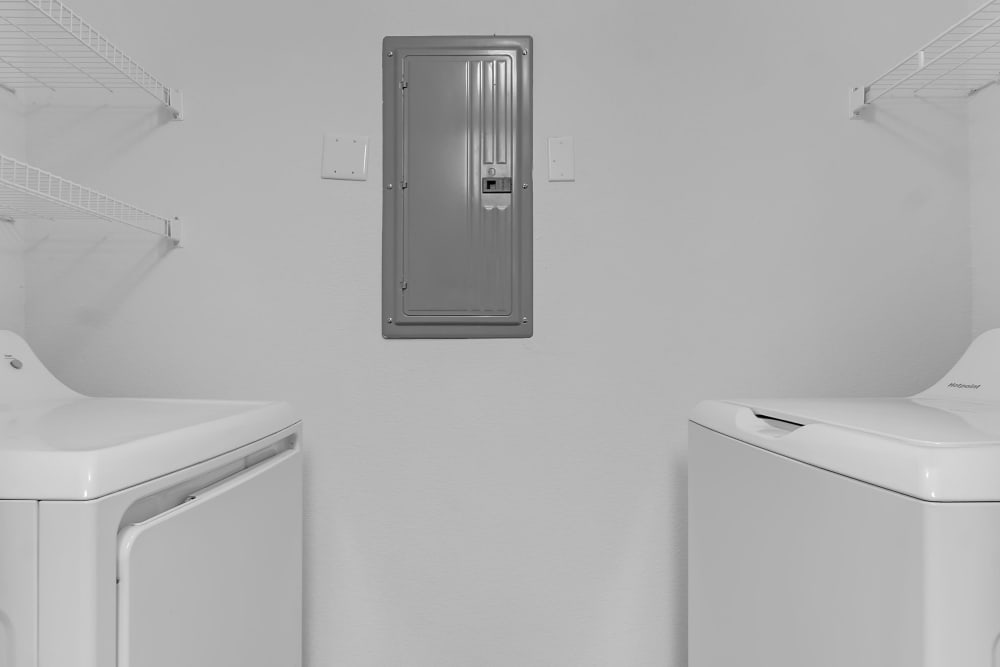 Bright laundry room with modern appliances and storage shelves at Wickham Gardens in Sapulpa, Oklahoma