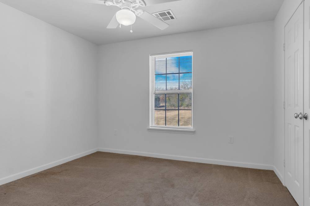 Bright, empty bedroom with natural light and ceiling fan at Wickham Gardens in Sapulpa, Oklahoma