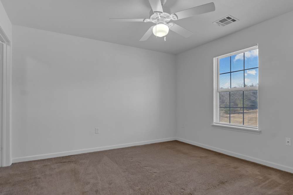 Bright, airy bedroom with plush carpet and ceiling fan at Wickham Gardens in Sapulpa, Oklahoma