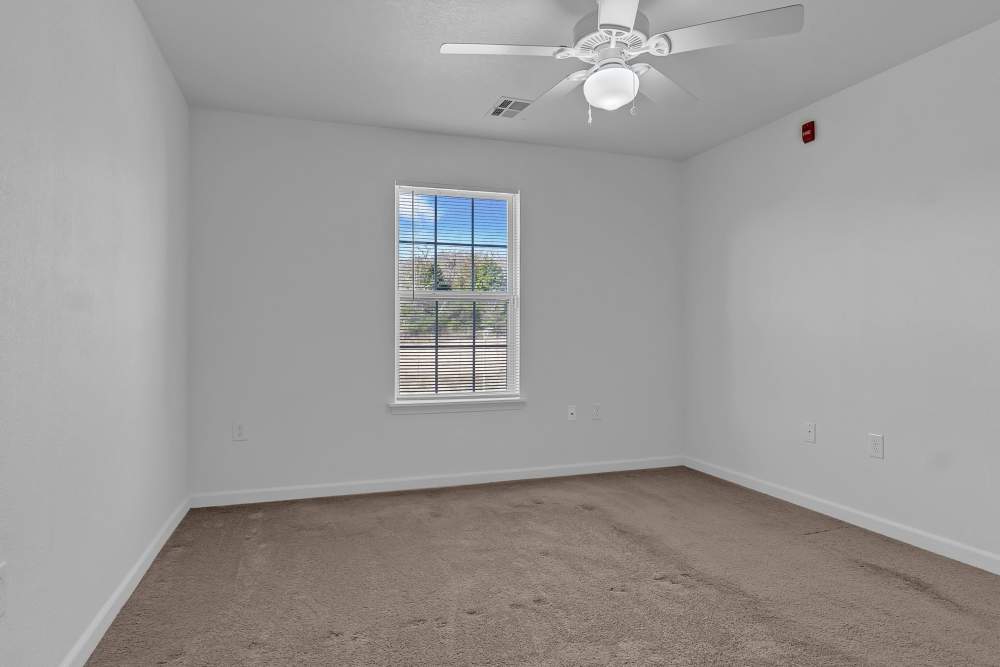 Bright, empty bedroom with natural light and ceiling fan at Wickham Gardens in Sapulpa, Oklahoma