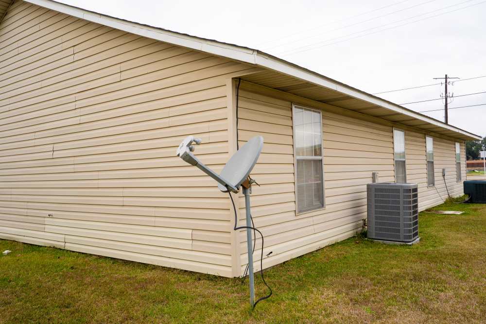Apartment home with vinyl siding and a central AC unit mounted in the yard at Willowbrook II in Lafayette, Louisiana
