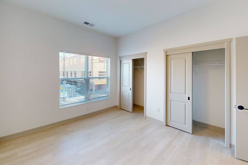 Bedroom with large window, dual closets, and light wood floors at Terra Station, Hudsonville, Michigan