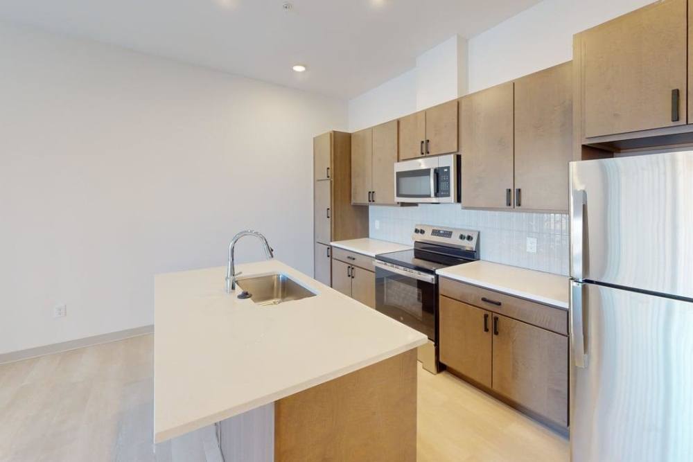 Modern kitchen with wood cabinets, stainless appliances, and island sink at Terra Station, Hudsonville, Michigan
