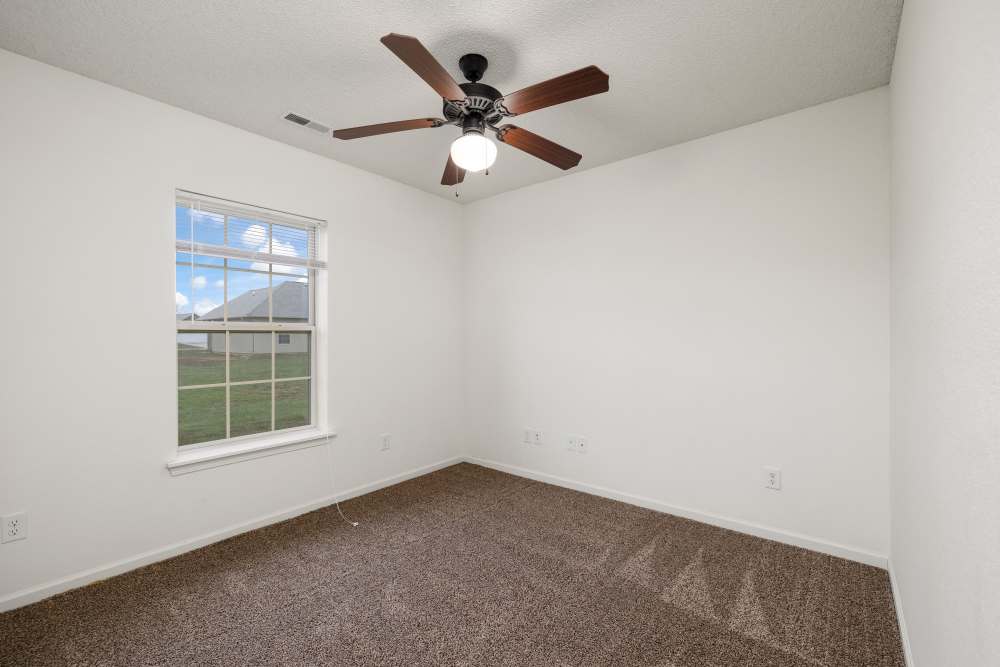Unfurnished bed room with ceiling fan and large window outside view at Oaklawn Estates in Rogersville, Missouri 