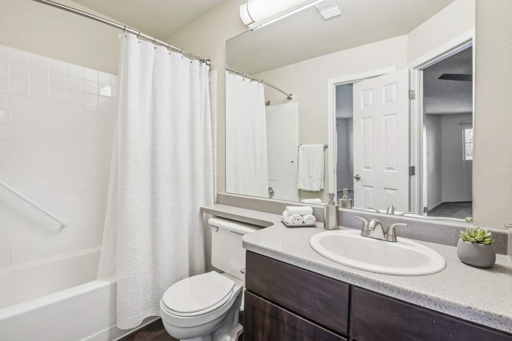 Recently renovated bathroom with brown cabinets and a large tub at Bluesky Landing Apartments in Lakewood, Colorado