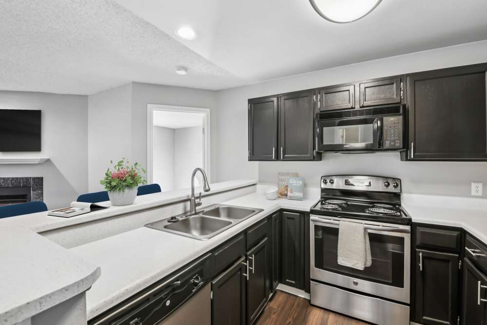 Kitchen with stainless-steel appliances and raised bar countertop at Bluesky Landing Apartments in Lakewood, Colorado
