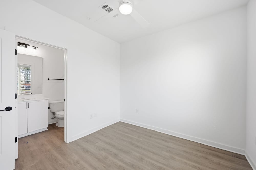 Empty bedroom with wood floors and attached bathroom at The Millwright in Cornelius, North Carolina