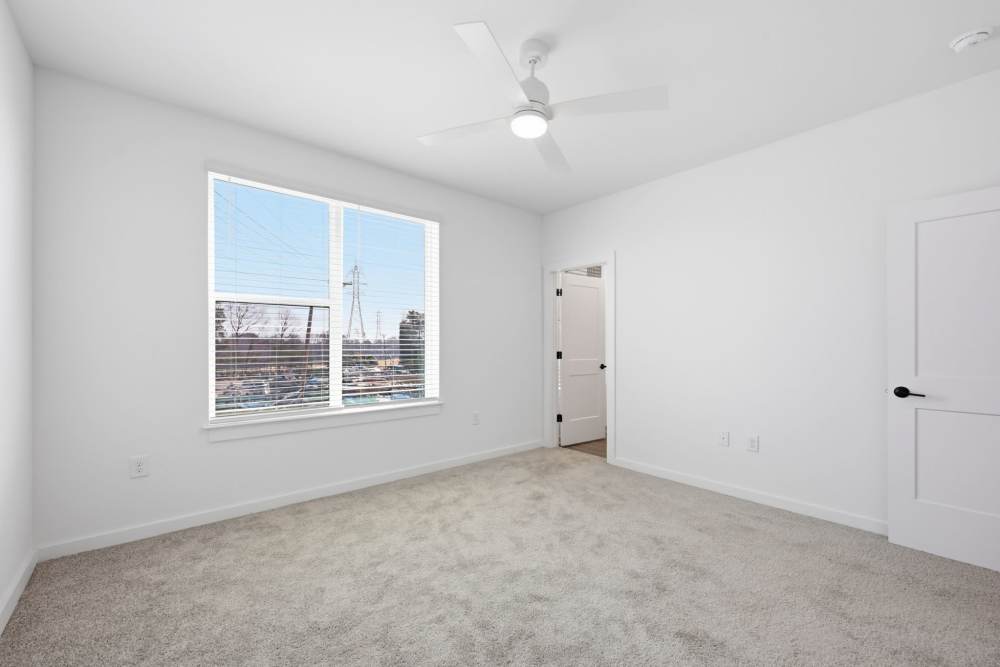 Bedroom with large window and carpet flooring at The Millwright in Cornelius, North Carolina