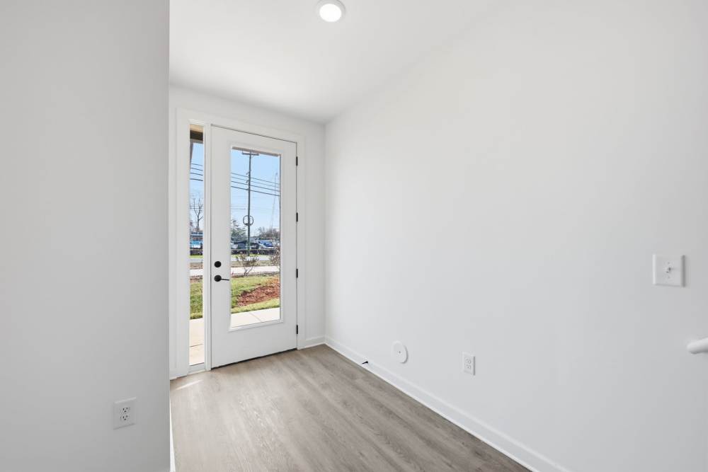 Bright entryway with glass door and wood flooring at The Millwright in Cornelius, North Carolina