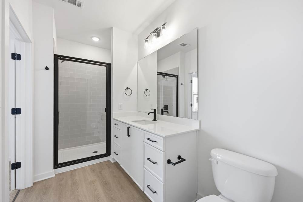 Bathroom with long vanity and glass shower at The Millwright in Cornelius, North Carolina