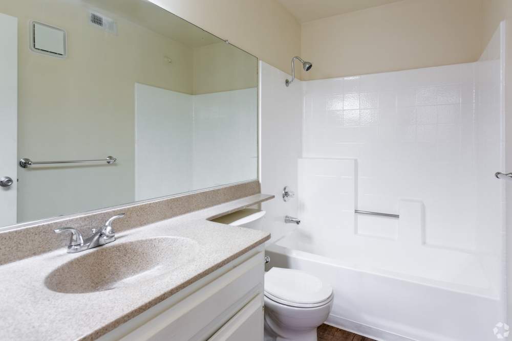 Bright apartment bathroom with vanity and shower‑tub at Sunrise Fountains in Anaheim, California.