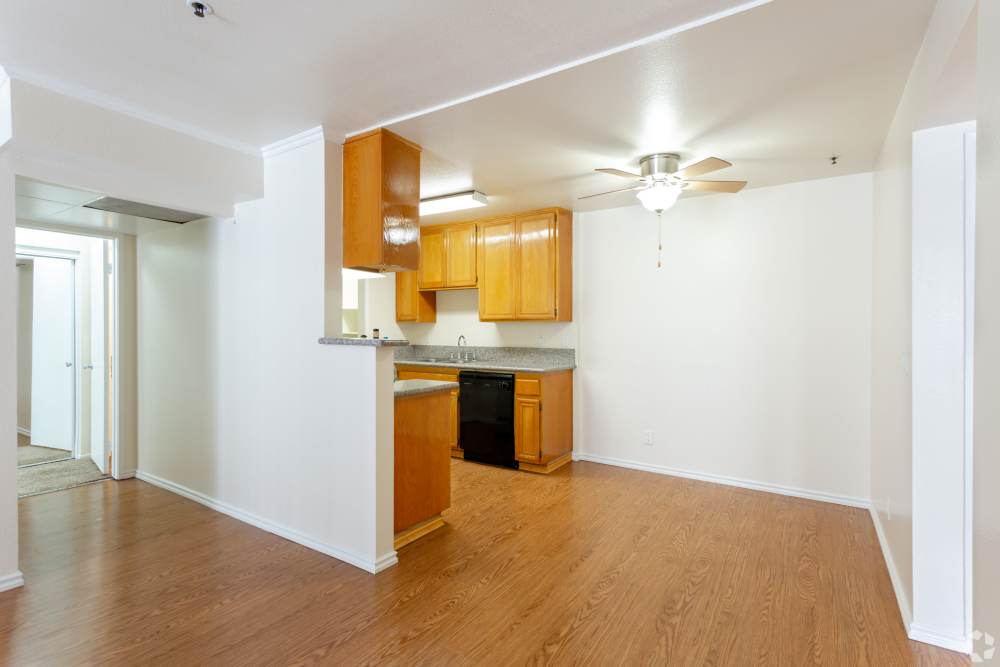 Apartment interior with wood flooring and open kitchen at Sunrise Fountains in Anaheim, California.
