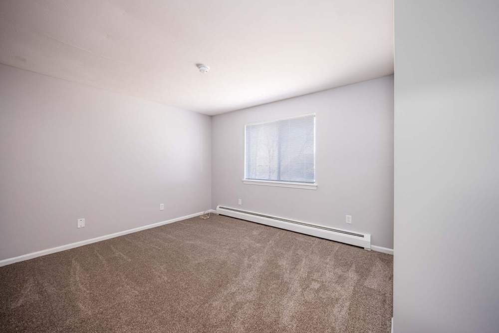 Unfurnished bedroom with large windows and carpeted flooring at Eastway Manor Apartments in Webster, New York
