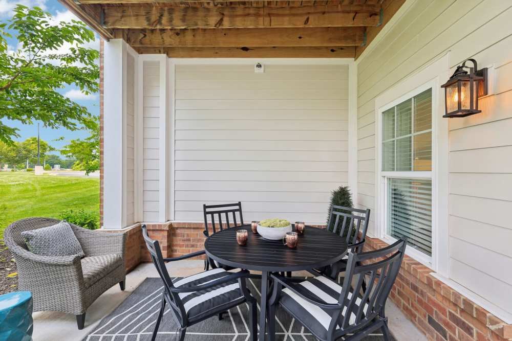 Covered patio with round dining table, four chairs, and outdoor seating area at The Drake in Bowling Green, Kentucky
