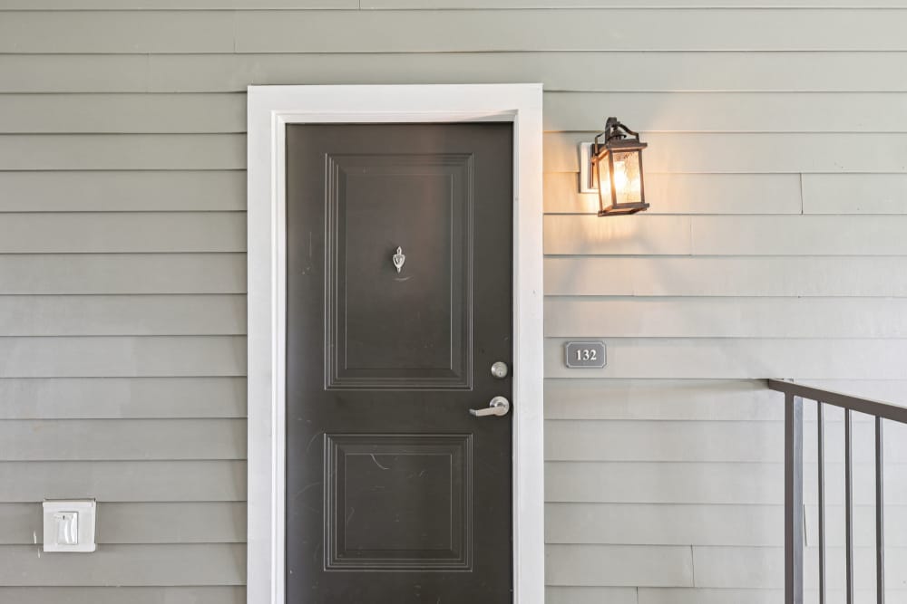 Exterior door labeled 132 with wall lantern against light gray siding at The Drake in Bowling Green, Kentucky