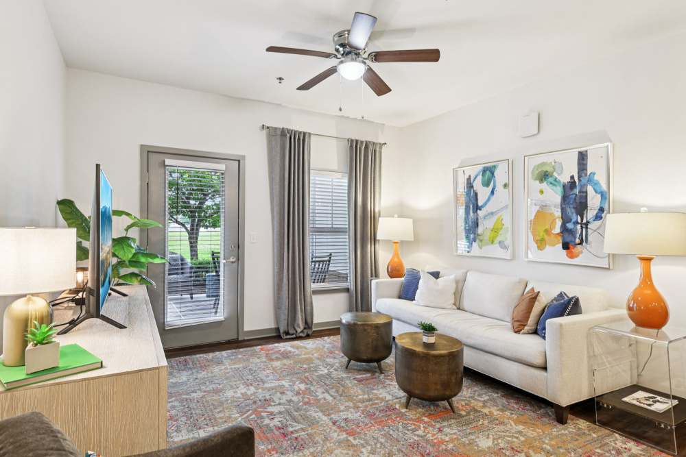Living room with sofa, TV stand, two round tables, and art on wall at The Drake in Bowling Green, Kentucky  