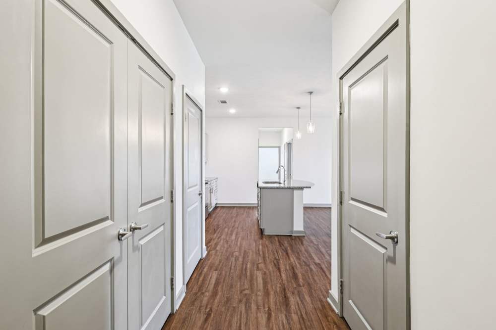 Hallway with wood flooring leading to kitchen with granite island and pendant lights at The Drake in Bowling Green, Kentucky  