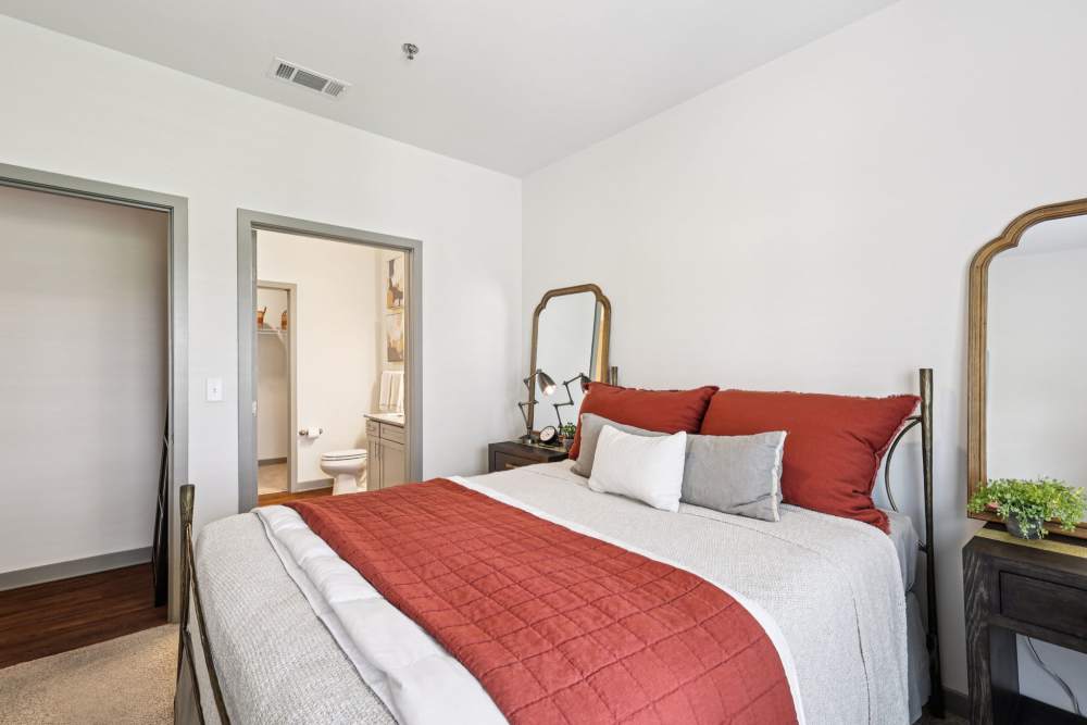 Bedroom with made bed, side tables, and doorway leading to bathroom at The Drake in Bowling Green, Kentucky  