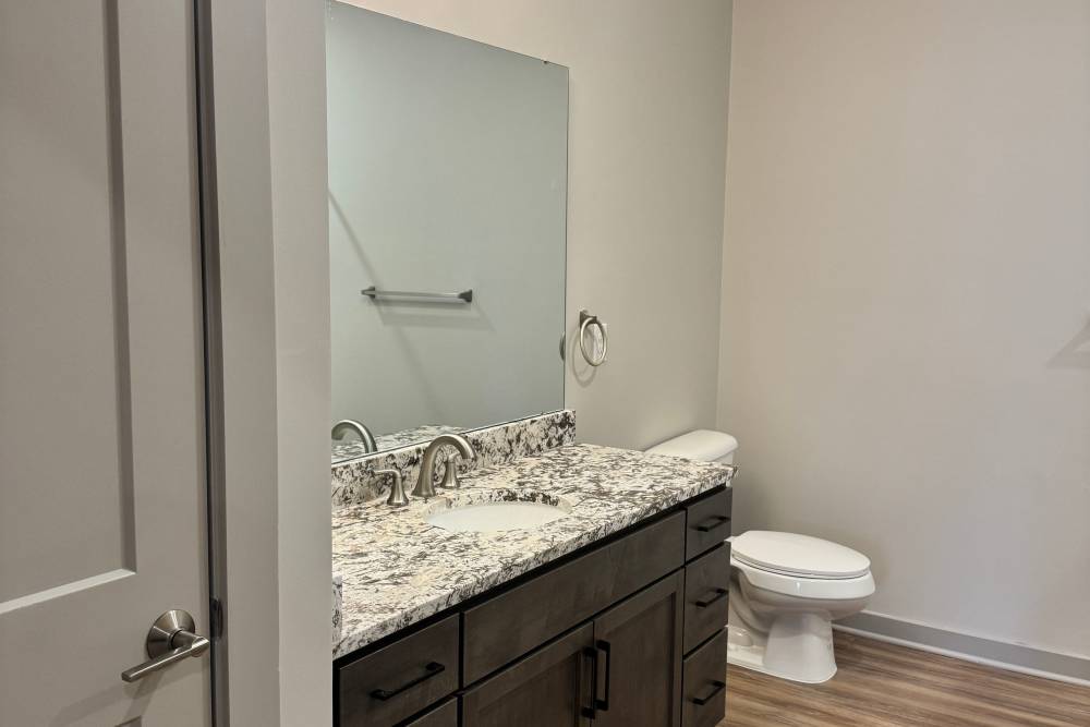 Bright bathroom hard flooring, waterfall faucet sink at Stride in Durham, North Carolina