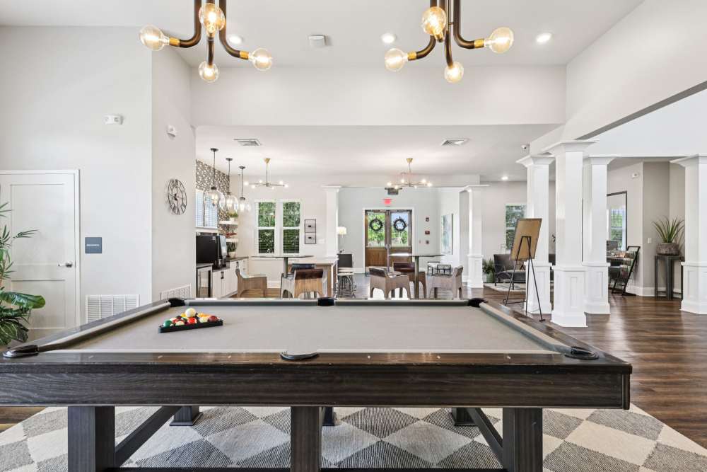 Room with pool table on patterned rug and open view into café area at The Drake in Bowling Green, Kentucky