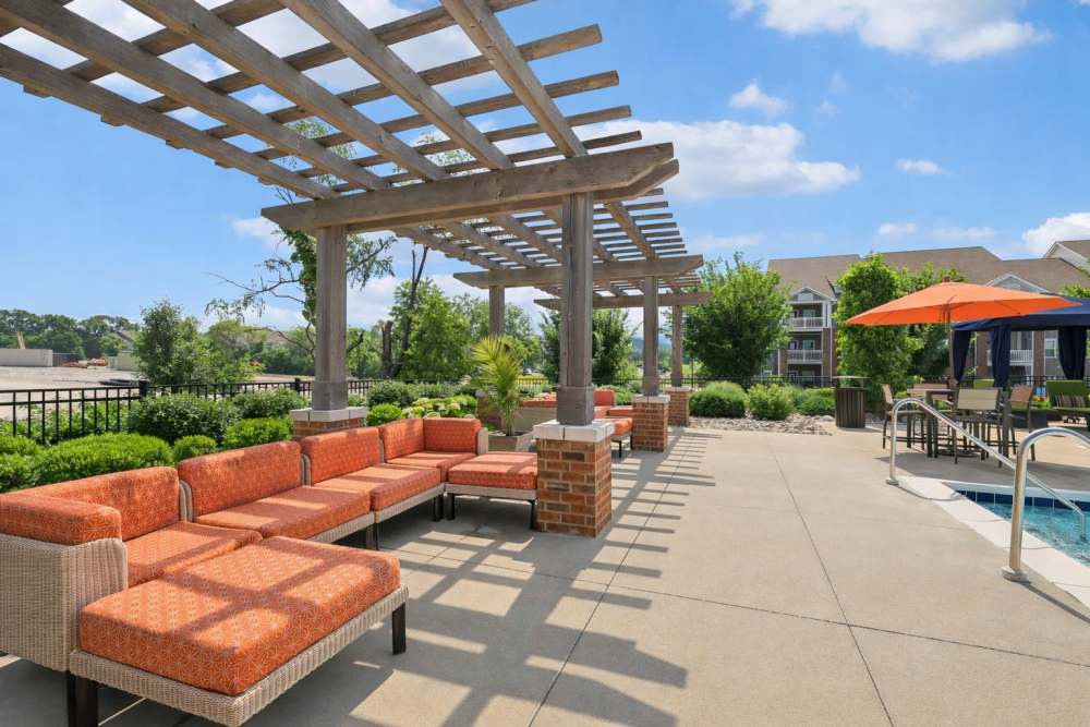 Outdoor pergola with orange cushioned seating beside landscaped pool area at The Drake in Bowling Green, Kentucky