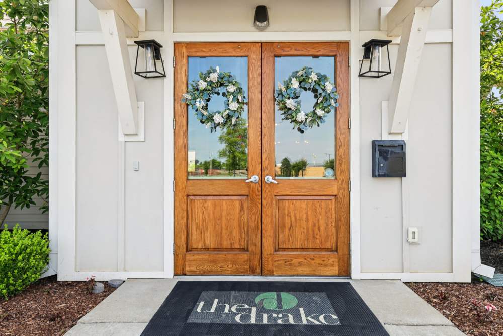 Entrance with double wooden doors decorated with wreaths and a rug reading “the drake at The Drake in Bowling Green, Kentucky