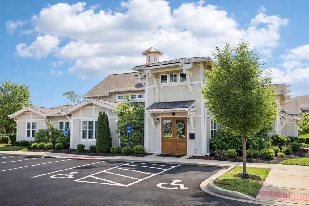 Clubhouse exterior with wooden double doors, landscaping, and accessible parking spaces at The Drake in Bowling Green, Kentucky