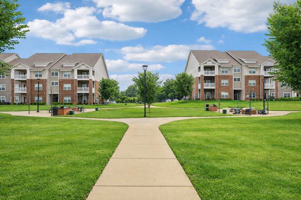 Wide grassy courtyard with walkway between two rows of apartment buildings at The Drake in Bowling Green, Kentucky