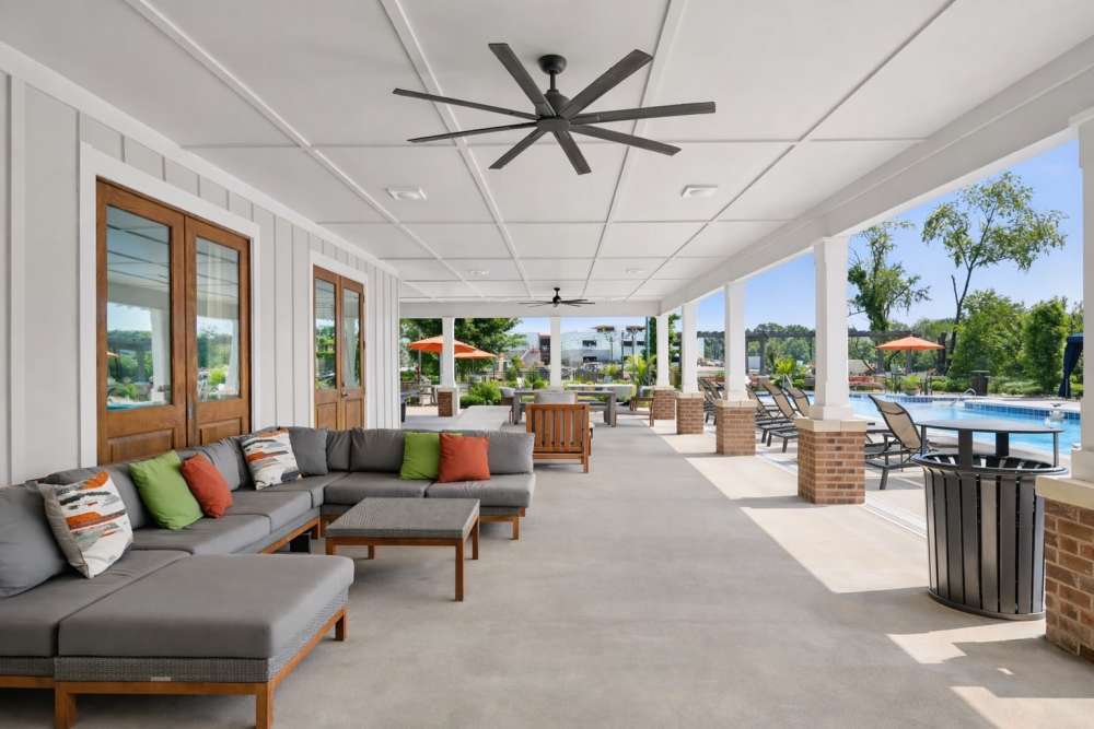 Covered lounge area with sectional seating, ceiling fans, and view of poolside seating at The Drake in Bowling Green, Kentucky