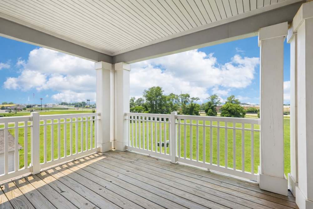 Covered balcony with white railing and view of open grassy field under blue sky at The Drake in Bowling Green, Kentucky