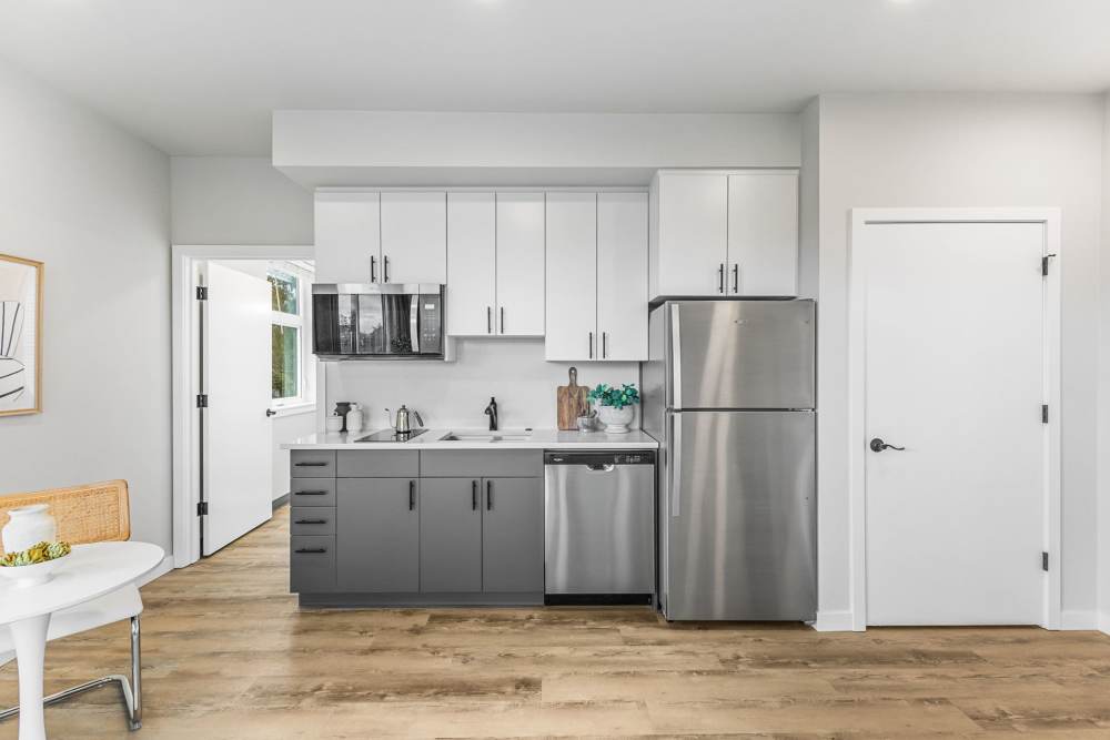 Modern kitchenette with white cabinets and stainless appliances at Cartwright Apartments in Salem, Oregon