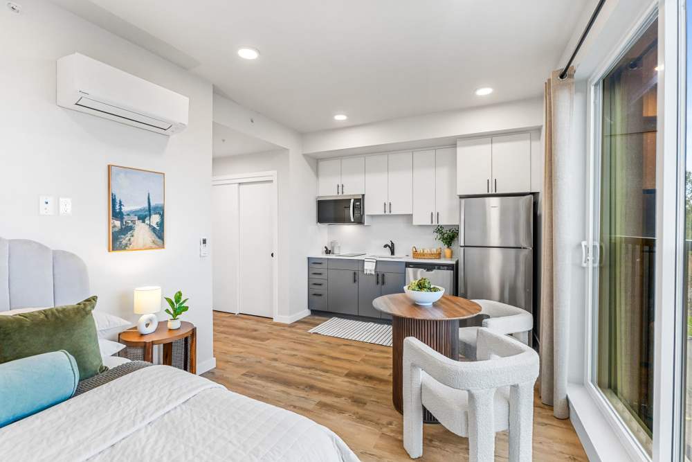 Open studio with bed, round dining table, and modern kitchenette at Cartwright Apartments in Salem, Oregon