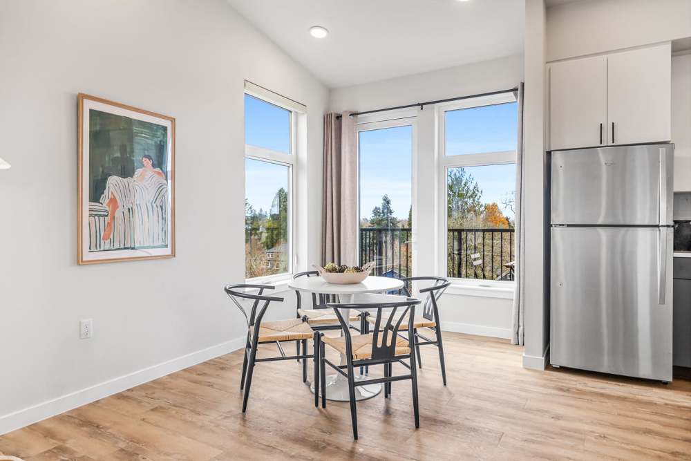Dining nook with round table and modern chairs by large windows at Cartwright Apartments in Salem, Oregon