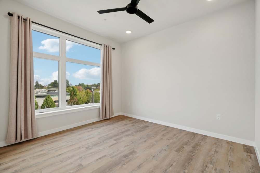 Bedroom with large window, wood floors, and ceiling fan at Cartwright Apartments in Salem, Oregon